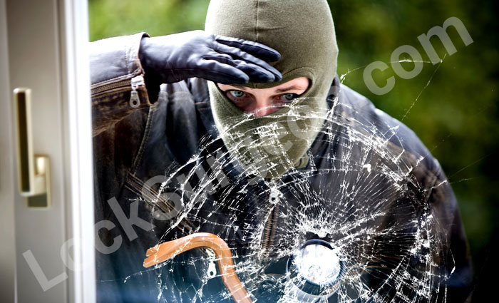 Burglar peering into home through smashed window.